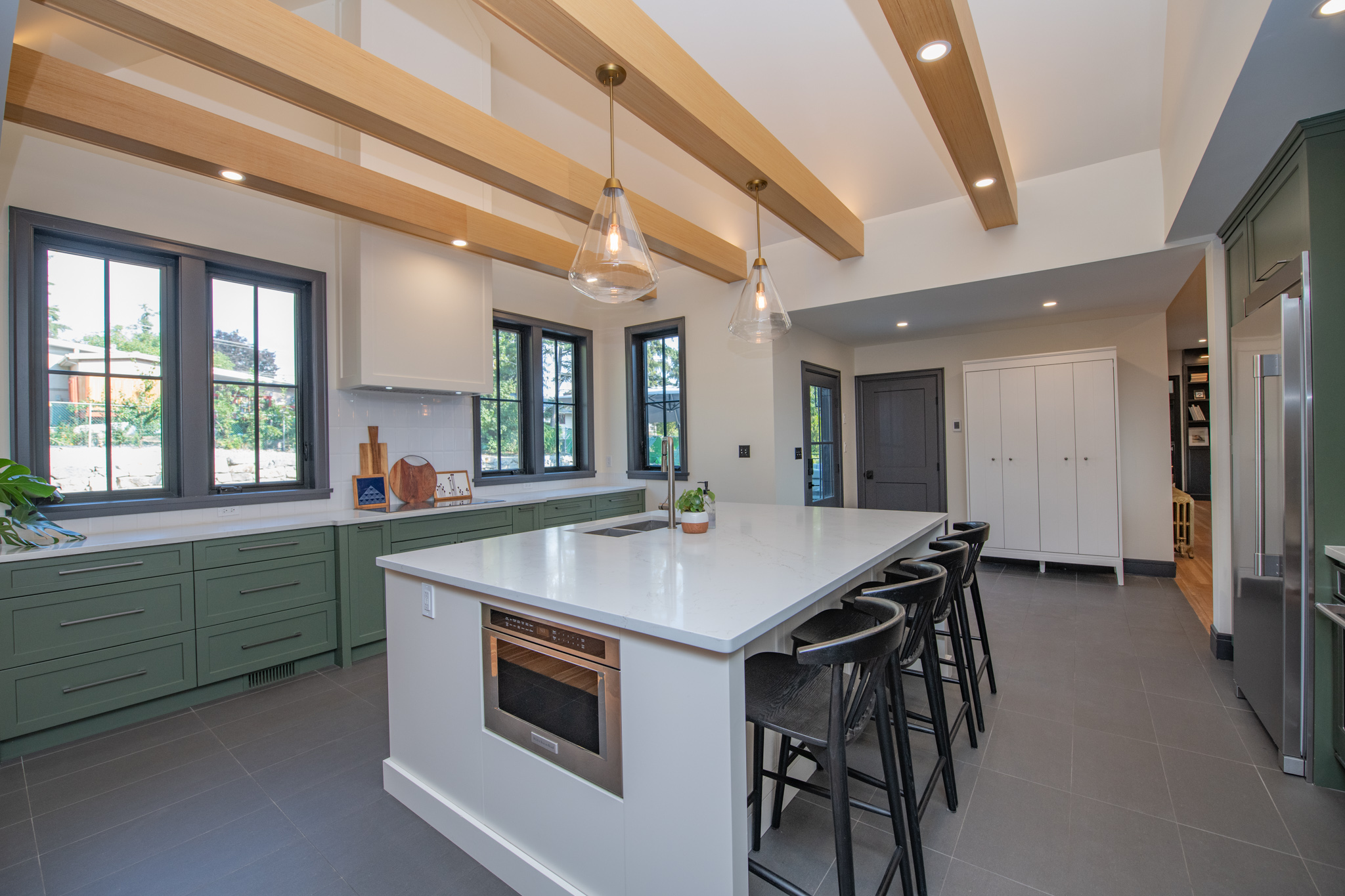 Chef’s kitchen with large island, beams and black window trim